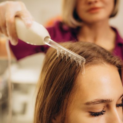 Beautician performs a professional procedure for the treatment of hair with darsonval