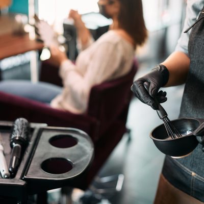 Close-up of hairstylist mixing hair dye while working at the salon.